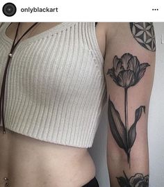 a woman's arm with tattoos on it and a flower tattoo on the side