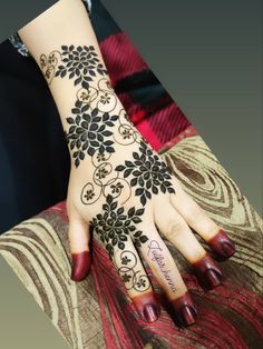 a woman's hand with black and white flowers on her left arm, painted in hendi