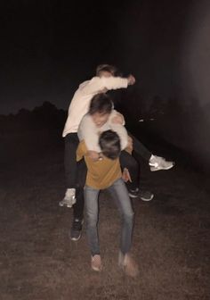 two men are hugging each other while standing in the grass at night with their arms around one another