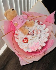 a teddy bear sitting on top of a bunch of flowers in a pink wrapper