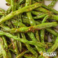 cooked green beans on a white plate with seasoning sprinkled in the middle