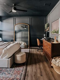 a bedroom with a bed, dresser and mirror on the wall next to a rug