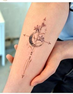 a woman's arm with a tattoo on it that has an arrow and flowers