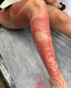 a woman laying on top of a bed covered in tattoos