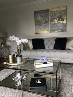 a living room with a couch, coffee table and two paintings on the wall behind it