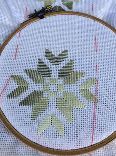 a close up of a cross stitch pattern on a white cloth with a wooden frame