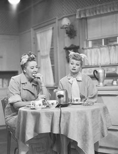 an old black and white photo of two women sitting at a table with tea cups