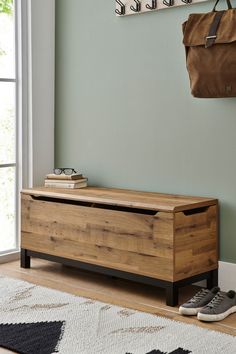 a wooden bench sitting on top of a hard wood floor next to a wall mounted coat rack