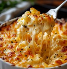 a spoon full of macaroni and cheese being lifted from a casserole dish