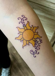 a woman's arm with a yellow and purple tattoo design on the left forearm