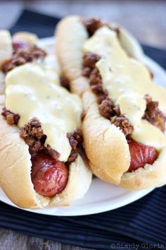 two hot dogs covered in cheese on a plate