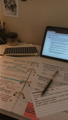 a laptop computer sitting on top of a desk covered in papers and writing utensils