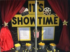 popcorn buckets are sitting in front of a movie show sign with red drapes