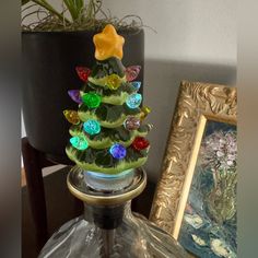 a glass christmas tree sitting on top of a table next to a potted plant