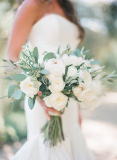 a bride holding a bouquet of white flowers