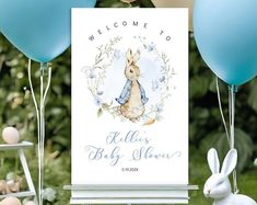 a welcome sign for a baby shower with blue balloons and bunnies in the background