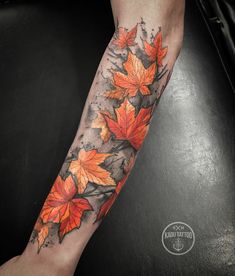 an orange and black leaf tattoo on the arm