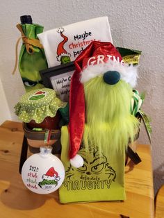 a green stuffed animal wearing a santa hat next to other holiday items on a table