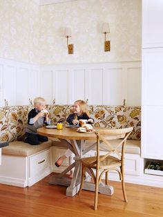 two children sitting at a table eating food