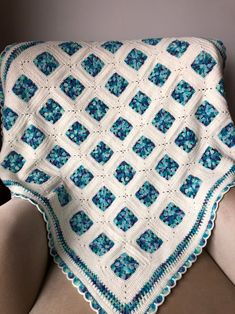 a blue and white crocheted blanket sitting on top of a couch