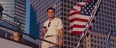 a man standing on top of a boat next to an american flag in the city