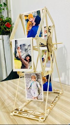 an easel with pictures on it sitting on top of a wooden table next to a potted plant