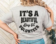 a woman wearing a gray shirt that says it's a beautiful day to volunteer