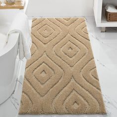 a bath room with a toilet and a rug on the floor in front of a tub