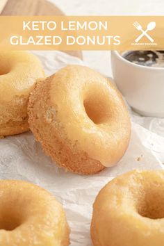 three doughnuts sitting on top of wax paper next to a cup of coffee