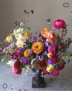 a vase filled with lots of colorful flowers on top of a white tablecloth covered floor