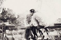 two people on skateboards leaning against a rail in front of some bushes and trees