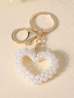 a heart shaped keychain with pearls hanging from it's side on a table