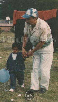 an old photo of a man holding a blue ball with a young boy standing next to him