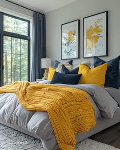 a bed with yellow and blue pillows in a bedroom next to a large glass window