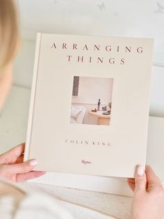 a woman holding up a book about arranging things