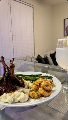 a white plate topped with meat and veggies next to a glass of wine