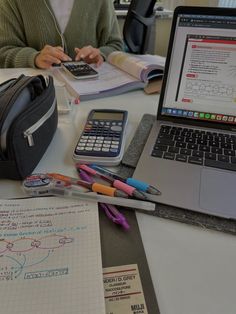 a laptop computer sitting on top of a desk next to a notebook and calculator