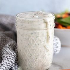 a jar filled with dressing next to a salad