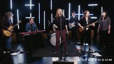 a group of people that are standing in front of some microphones and guitar's