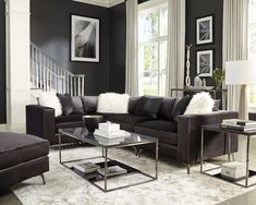 a living room filled with black furniture and white pillows on top of it's couches