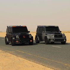 two black jeeps driving down the road in front of each other on a desert plain