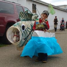 a young boy is dressed up as a fish and holding a plastic bag in his hand