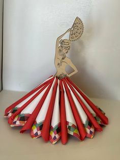 an ornament made out of red and white paper with a woman holding a tennis racquet