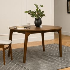 a wooden table with a plant on top of it next to a chair and rug