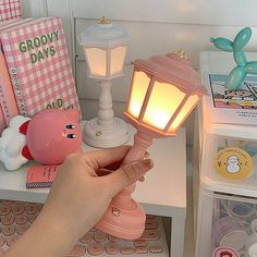 a person holding a small light on top of a white table next to other items