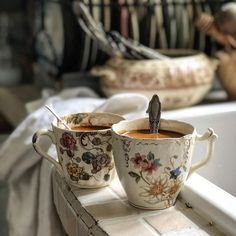 two coffee cups with spoons in them sitting on a counter