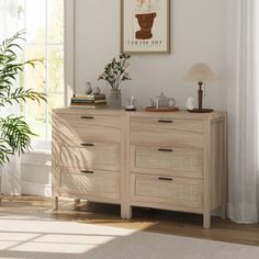 a living room with a large window and a plant on the side of the dresser