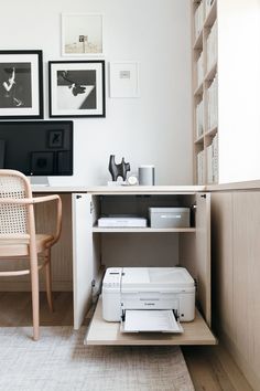 a white printer sitting on top of a wooden shelf next to a chair and desk