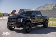 a black truck parked in front of a house with mountains in the backgroud