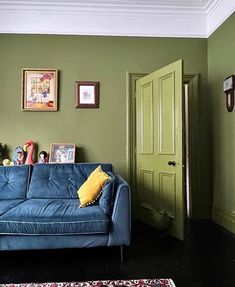 a living room with green walls and pictures on the wall above the blue couches